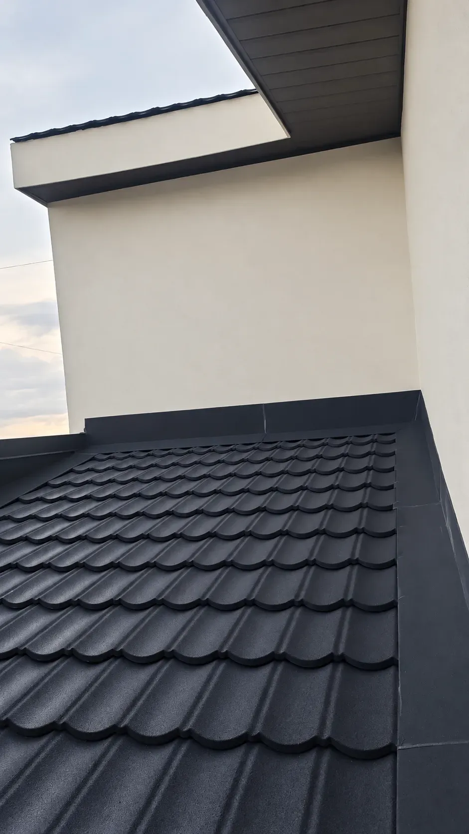 Techo de teja negra junto a una pared, con su remate lateral